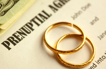 A prenuptial agreement under a stack of wedding rings